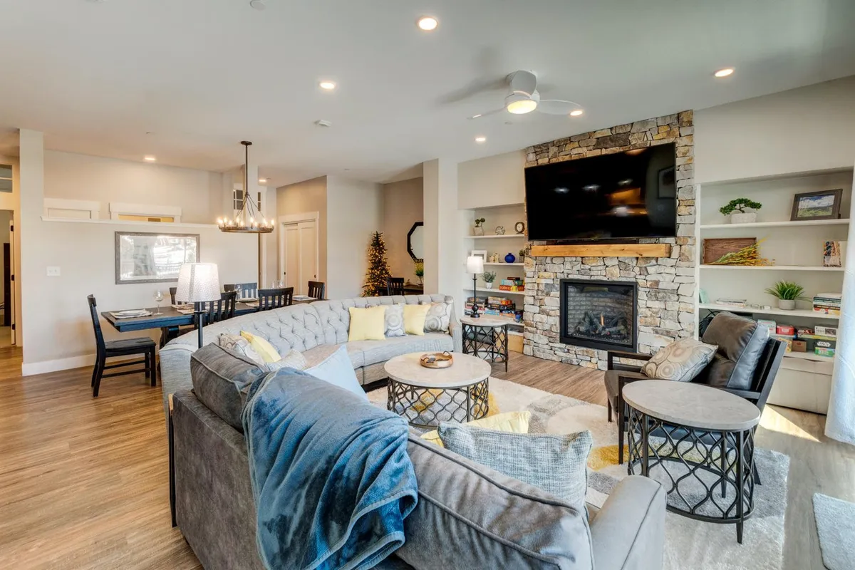 A cozy, inviting living room featuring a fireplace, comfy seating, coffee table, and decorative shelving. The space emanates warmth and comfort, ideal for relaxing after a day outdoors or for a pet to curl up and nap with their owner.