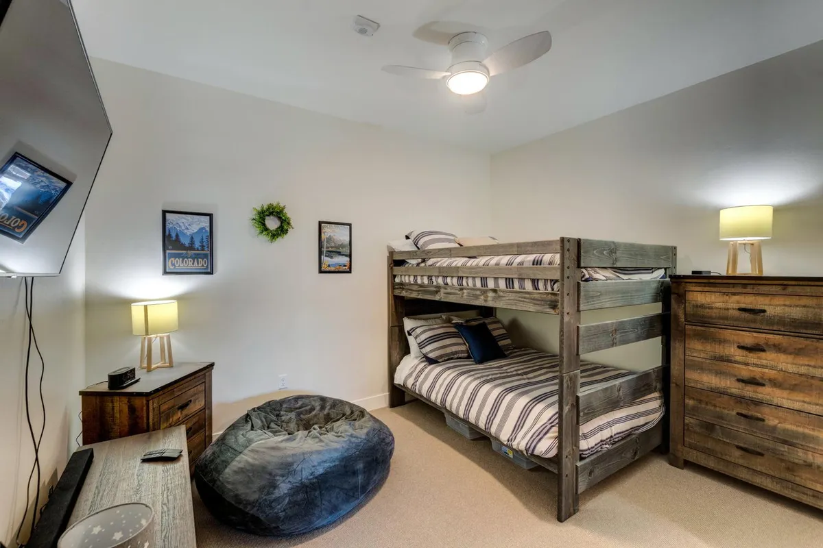 A playful bunk room set up with a bunk bed, bean bag chair, wooden dresser, and a television, creating a space that’s both fun and cozy for children or teens.